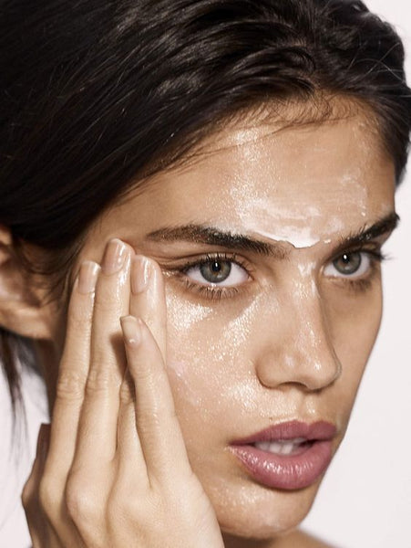 Woman applying UNISKIN Vitamin C Detox Natural Cleanser to her face with her hands.