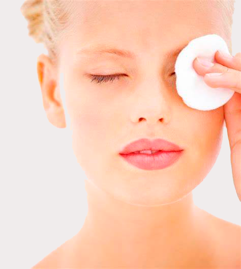 woman applying uniclean - detox cleanser to her face with a cotton pad.
